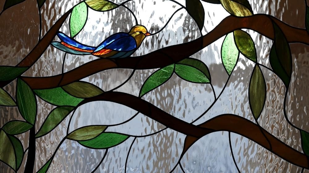 Una vidriera con un pájaro en una rama